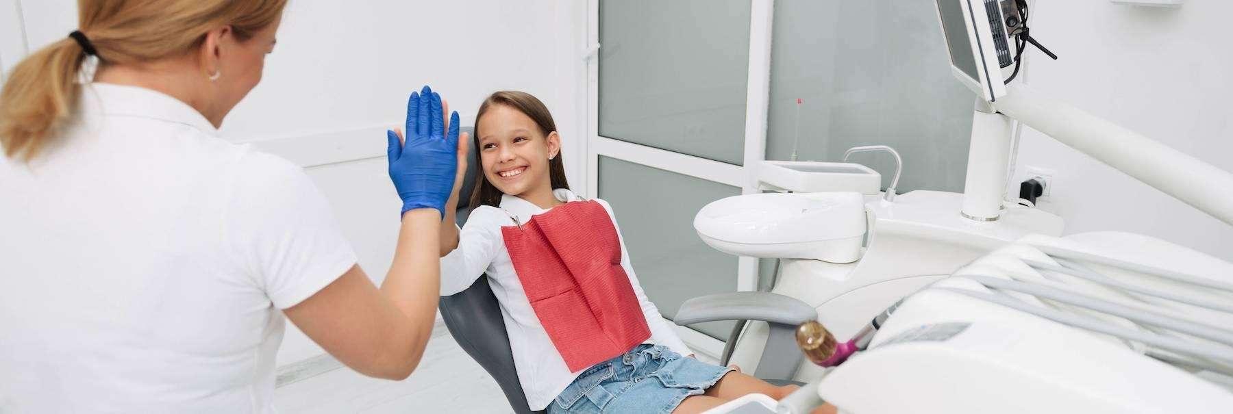 A smiling girl high-fiving her dentist