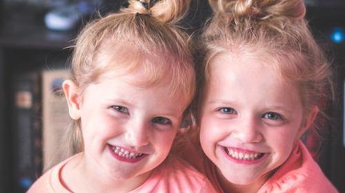 Twin girls in pink smiling